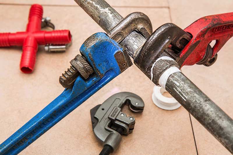 Two wrenches clamped on a metal pipe