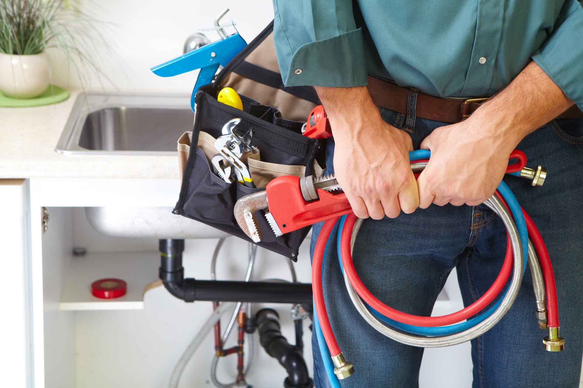 Plumber standing in front of kitchen sink with tool bag